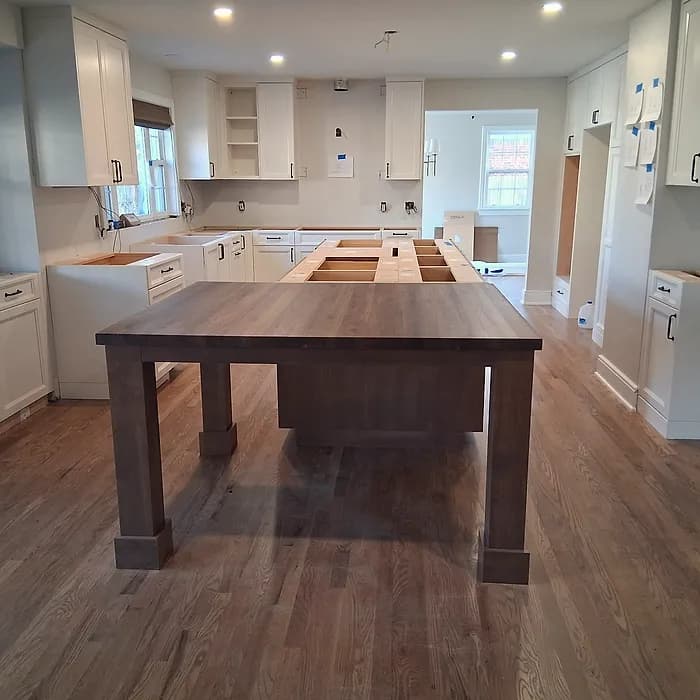 Custom solid-wood dining table in a renovated kitchen with white cabinetry